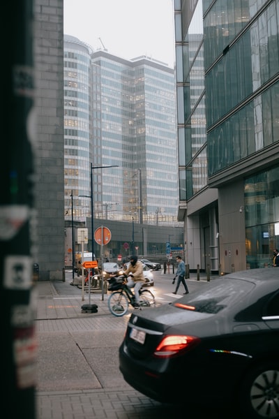 During the day, people in tall buildings near the road to ride a motorcycle
